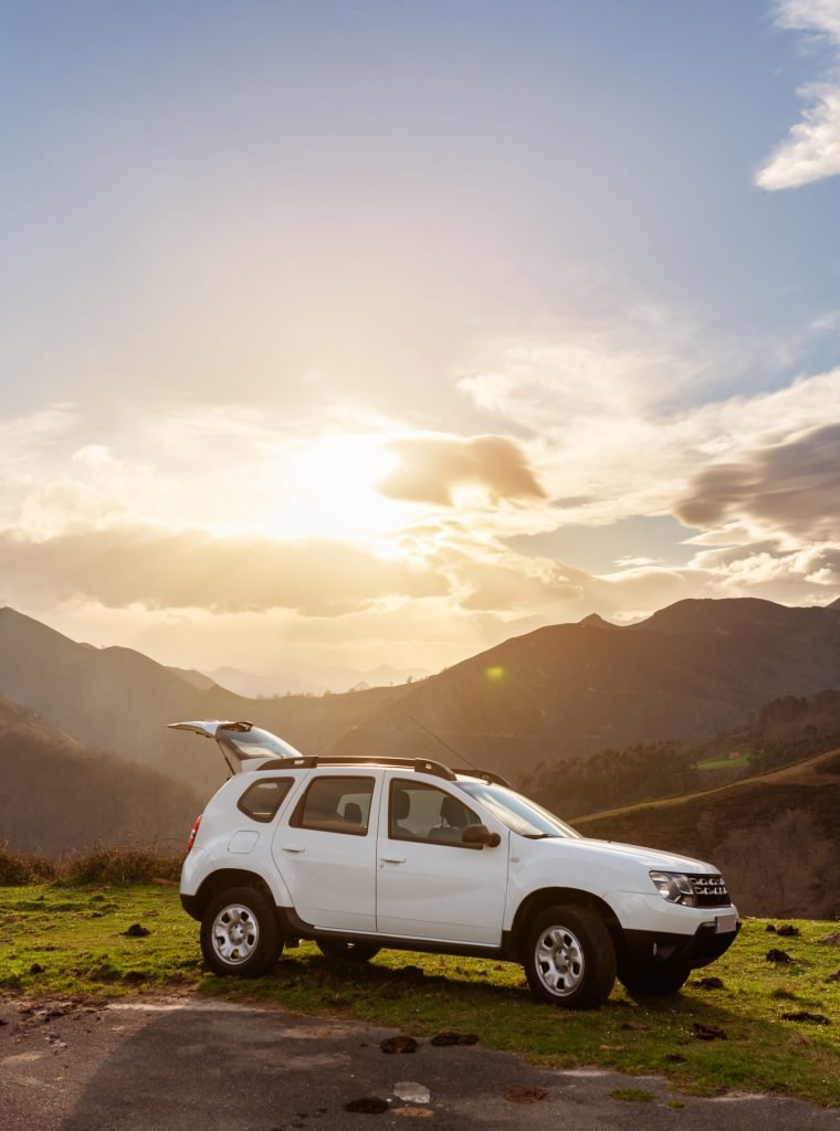 4wd off-road car with open trunk at sunset on the mountain. SUV vehicle perched in the field.